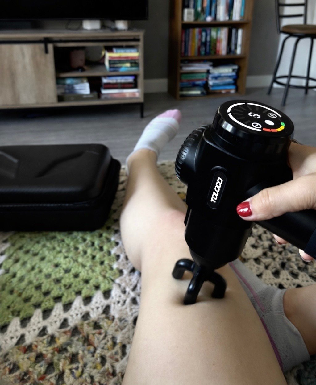 Using the TOLOCO massage gun on legs after a run